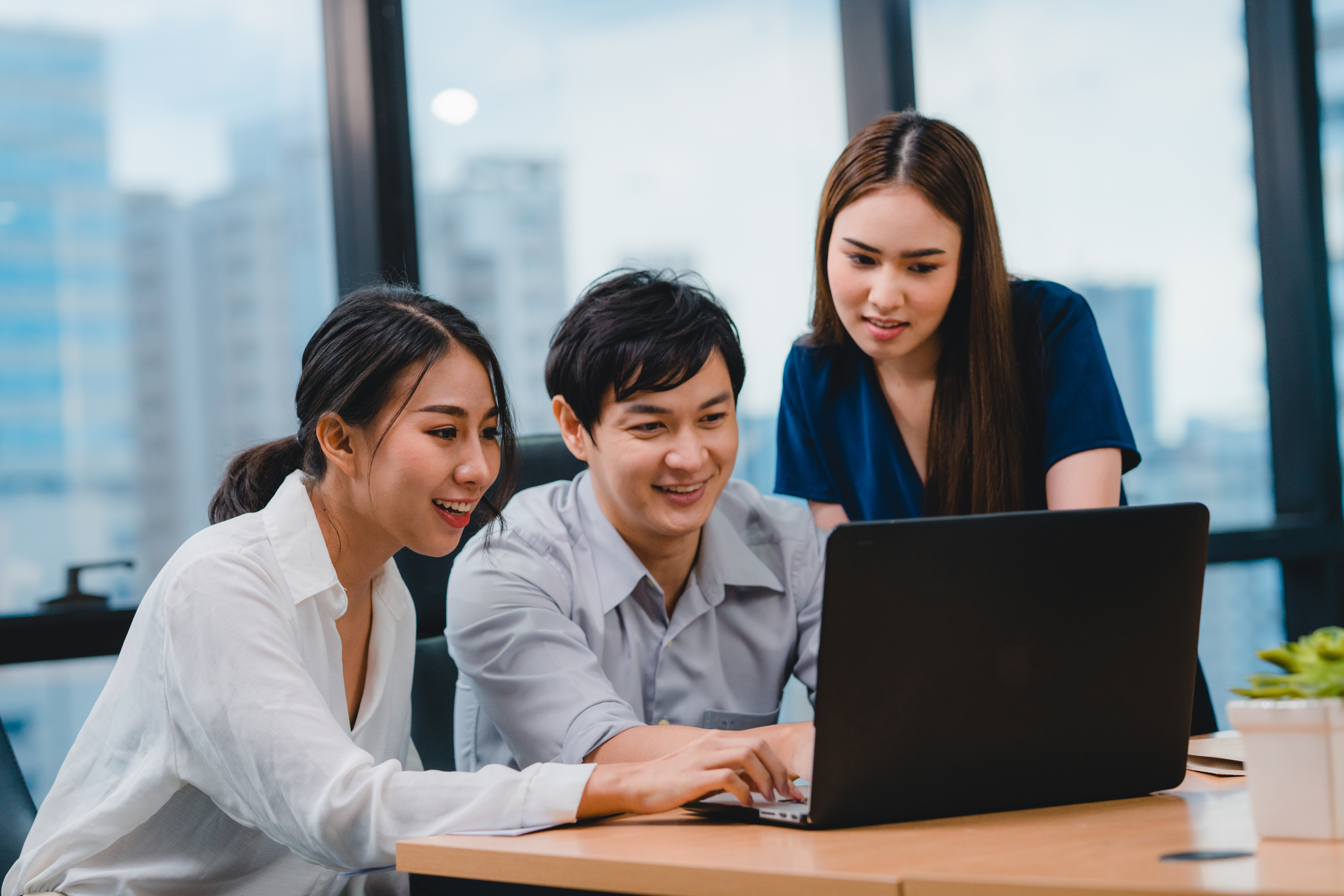 Nurses, support staff, and teammates working together around a laptop